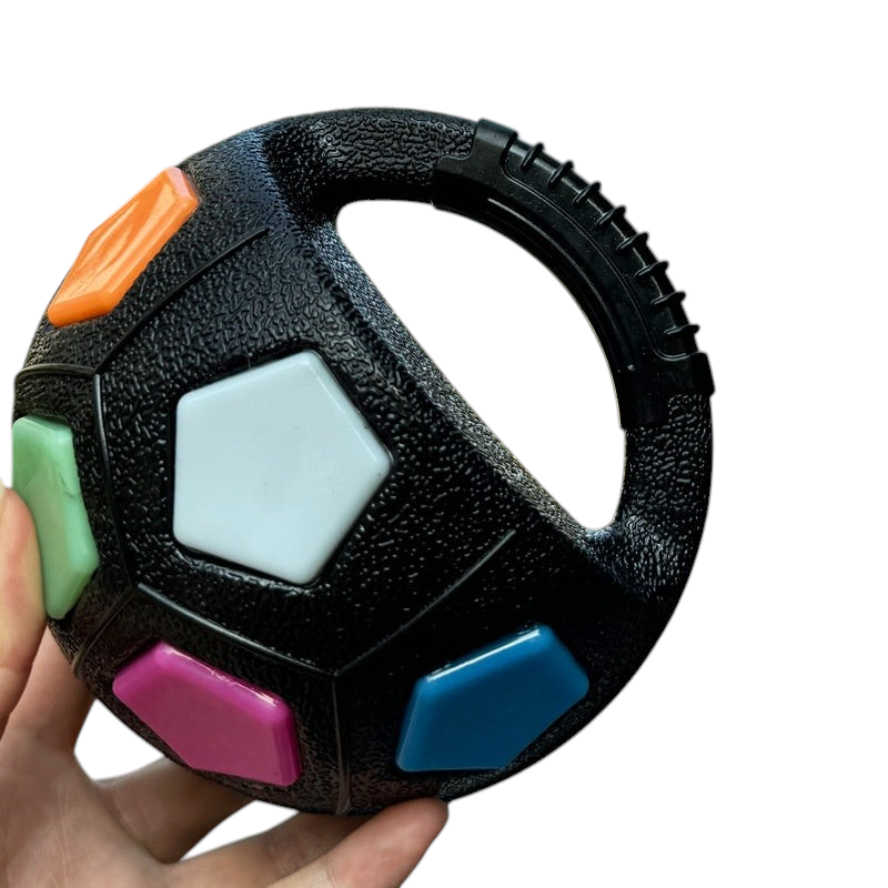 The Tailored Tail black interactive dog fetch ball with colorful pentagon accents and a sturdy handle for easy throwing.