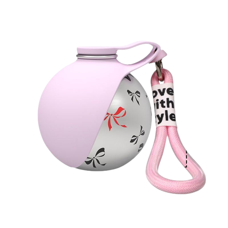 The Tailored Tail collapsible pet water bottle with a pink silicone top, stainless steel body, and bow print pattern.