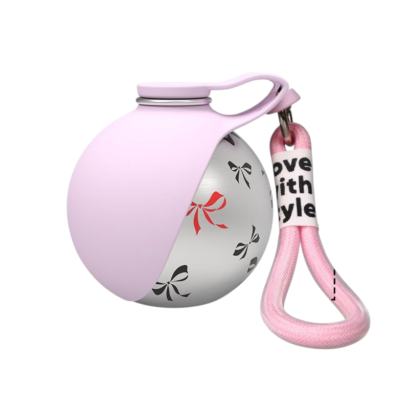 The Tailored Tail collapsible pet water bottle in pink with a stainless steel body featuring a bow print and hook.